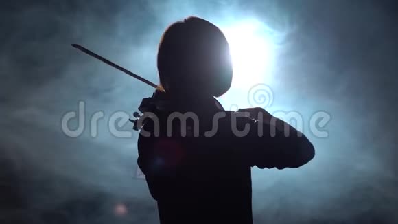 专业人士用灯笼在黑暗的工作室里拉小提琴黑烟背景背面视频的预览图