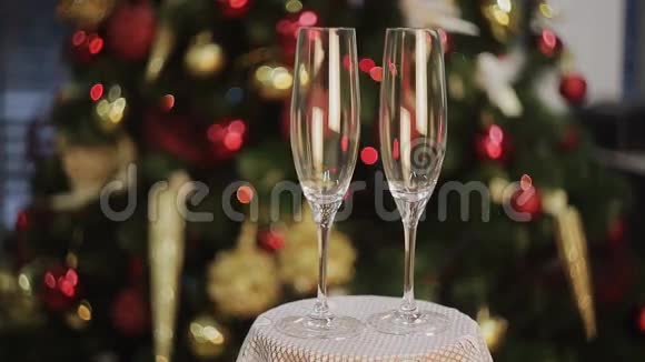 在圣诞树的背景上摆着香槟的空杯子视频的预览图