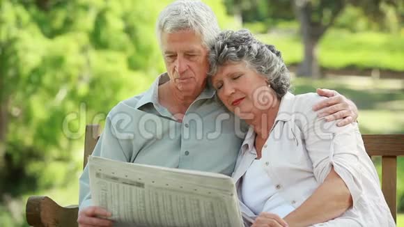 成熟的男人一边看报纸一边拥抱妻子视频的预览图