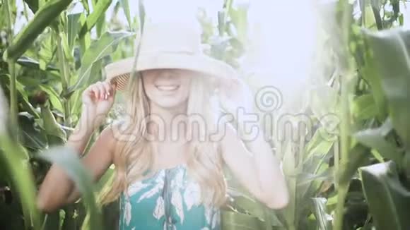 戴着帽子的漂亮女孩在玉米地慢动作中奔跑微笑视频的预览图