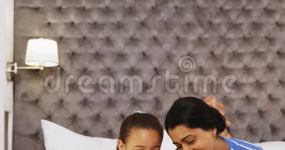 母亲和女儿在卧室里用数码平板电脑视频的预览图