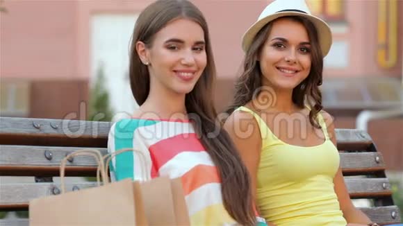 两个女孩购物后坐在长凳上视频的预览图