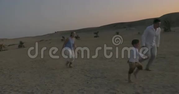 父母和儿子在海滩上踢足球视频的预览图