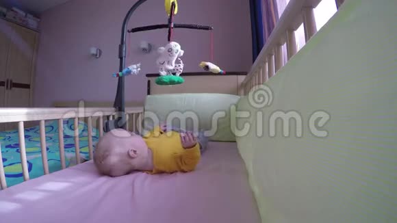 在木床上的婴儿试图抓住旋转木马玩具4K视频的预览图