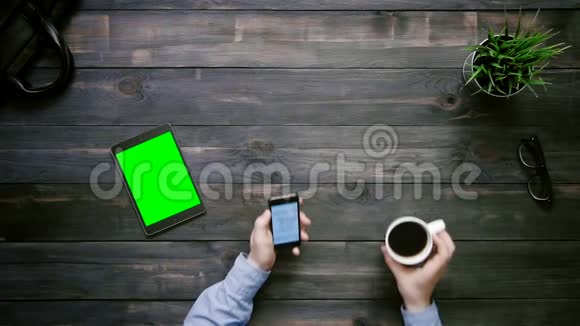 在智能手机和带有绿色屏幕的数字平板电脑上男性双手工作在大数据图表上视频的预览图