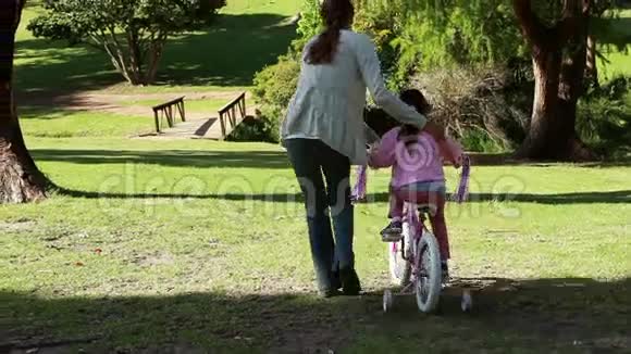 一个女人帮她女儿骑自行车的后视镜视频的预览图