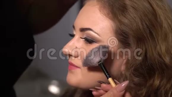 美容院年轻漂亮的女孩模特坐在椅子上化妆师给女孩化妆金发美女视频的预览图