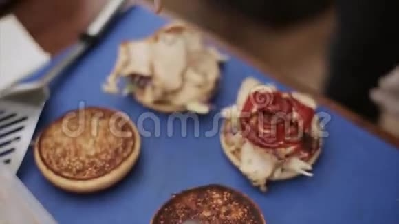 在准备好的汉堡和肉上倒入番茄酱的手套中烹饪快餐烤面包露天活动视频的预览图