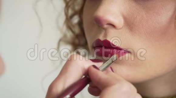 化妆师用刷子涂口红女性模特面部特写时尚光泽红唇化妆美丽视频的预览图