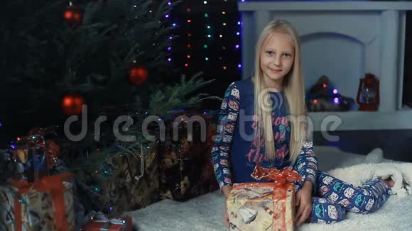 一个小女孩坐在圣诞树下正在考虑礼物视频的预览图