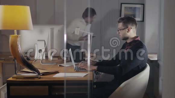 两位年轻的商人在会上用触摸板讨论数据现代办公室英俊的自由职业者视频的预览图