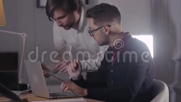 两位年轻的商人在会上用触摸板讨论数据现代办公室英俊的自由职业者视频的预览图