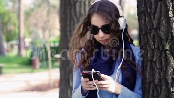 公园里戴着耳机听音乐的戴墨镜的美女视频的预览图