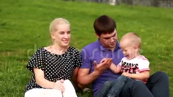 幸福的家庭爸爸妈妈和宝宝在草地上玩耍视频的预览图