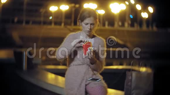 夜晚在户外的灯光下吃炸薯条的年轻女子视频的预览图