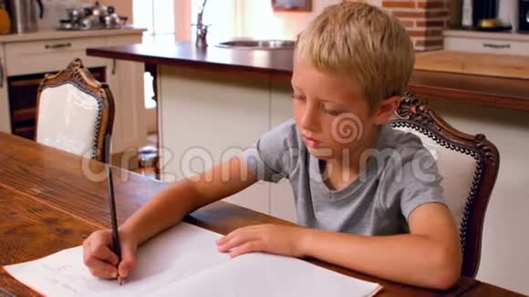 可爱的男孩在厨房桌子上做作业视频的预览图