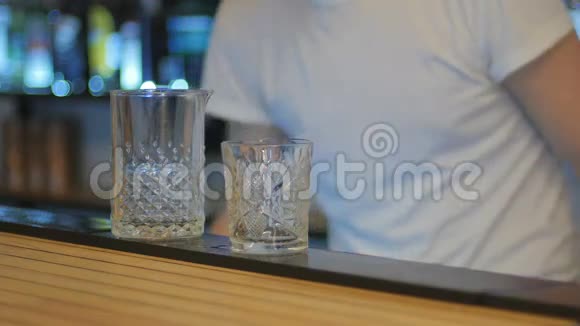 特写镜头酒保把冰放进玻璃杯里用勺子搅拌视频的预览图