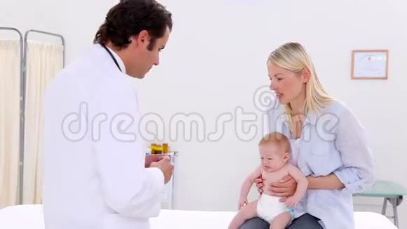 一位严肃的医生给婴儿看注射器视频的预览图