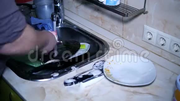 厨房里的人在洗碗池里快速地刷洗碗碟视频的预览图
