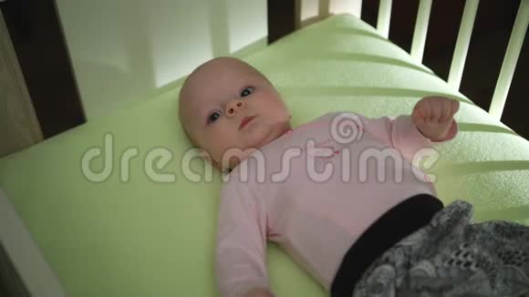 可爱的宝宝躺在床上双手活动穿着粉红色的布视频的预览图