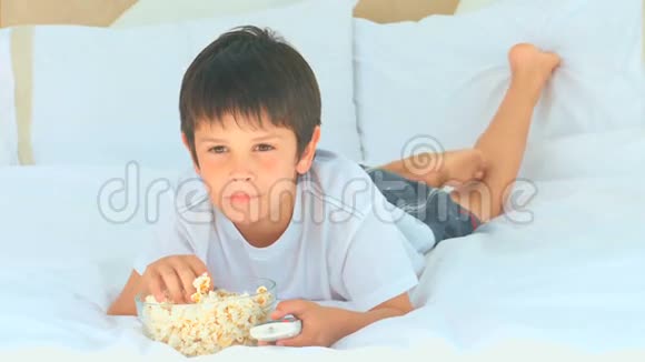 一个小男孩在电视机前吃爆米花视频的预览图