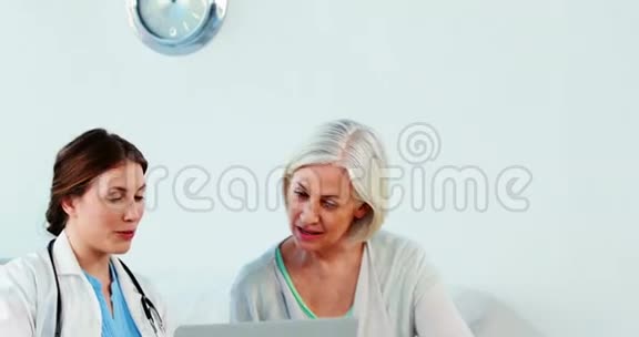 女性医生在使用笔记本电脑时与病人互动视频的预览图