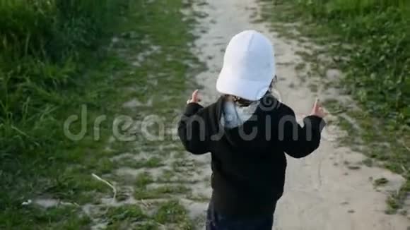 一个穿着带帽子的夹克的孩子在田野里奔跑视频的预览图