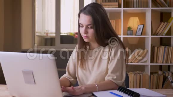年轻漂亮的白种人女商人用笔记本电脑在室内看着相机微笑的特写镜头视频的预览图