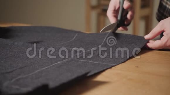裁剪深色羊毛面料线条图案年轻人做裁缝在车间里使用缝纫机视频的预览图