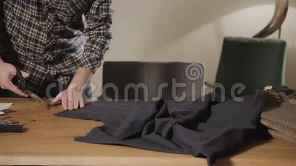 裁剪深色羊毛面料线条图案年轻人做裁缝在车间里使用缝纫机视频的预览图