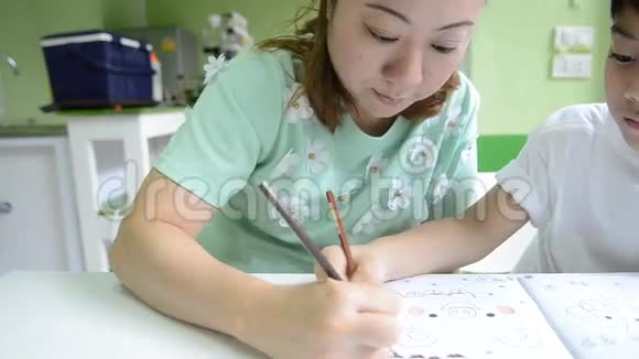 亚洲妈妈正在画她的儿子做学校的作业视频的预览图