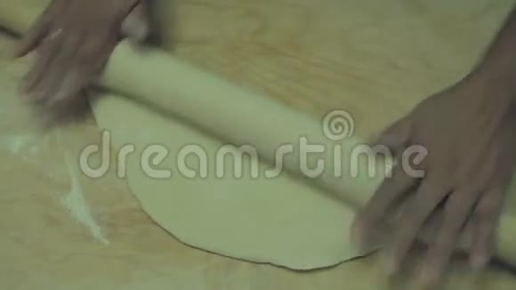 一个女人正在把面团擀在一个扁平的木头表面上视频的预览图