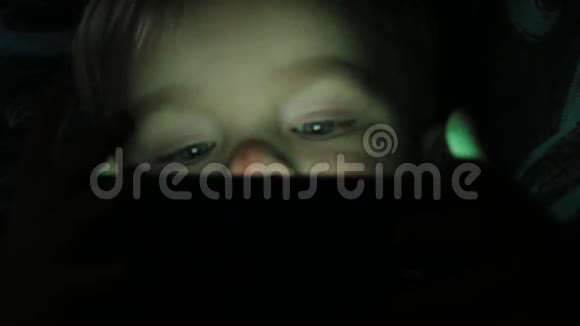两岁的男孩晚上在平板上看动画片视频的预览图