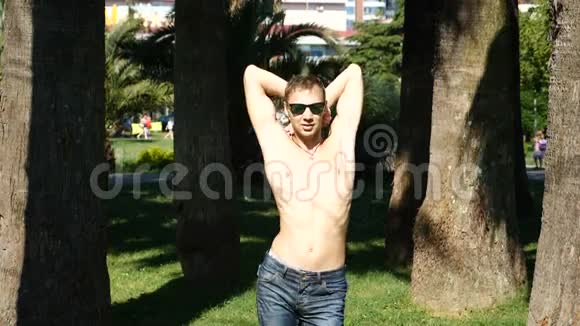 一个年轻快乐的家伙赤裸的躯干在一个夏季公园里跳舞跳现代芭蕾舞慢分子视频的预览图