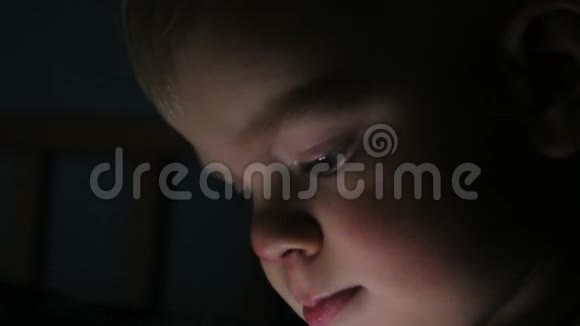 两岁的男孩晚上在平板上看动画片视频的预览图