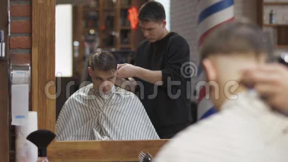 职业理发师用电动剃须刀给年轻人理发视频的预览图