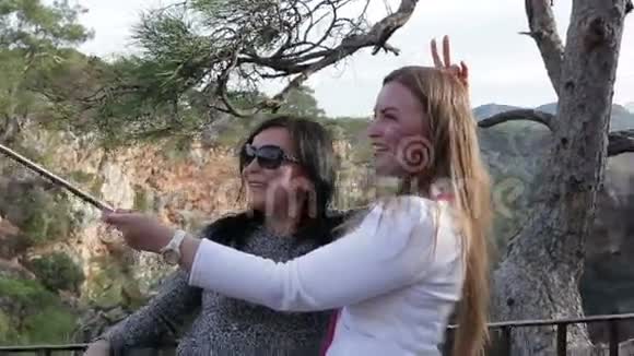 两个年轻漂亮的女人用智能手机拍照特写镜头视频的预览图