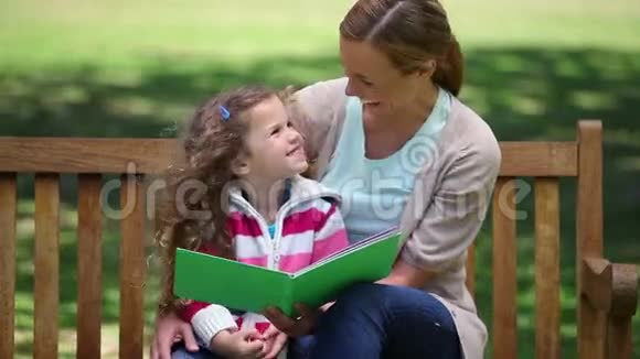 妈妈在长凳上给女儿读故事视频的预览图