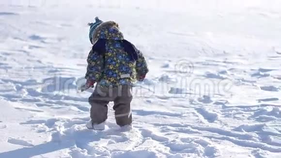 戴着冬帽的小男孩在雪地里玩耍视频的预览图