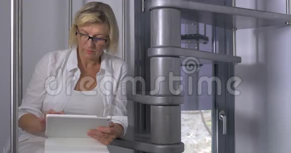 成年妇女坐在带有平板电脑的楼梯上视频的预览图