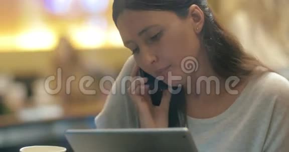 女人在咖啡馆里忙着打电话和用电话视频的预览图