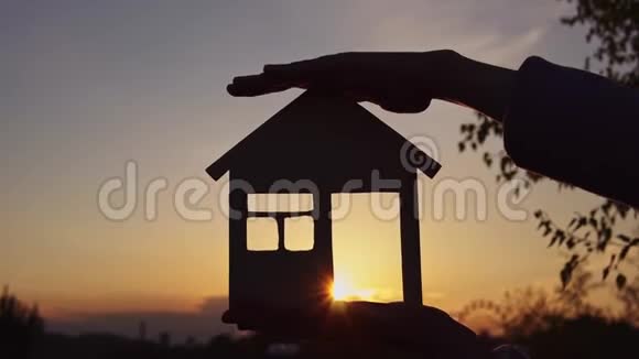 太阳落山时特写双手握住房子视频的预览图