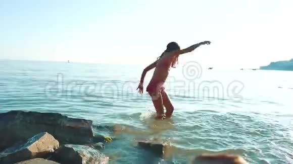 小女孩用石头和石头在海里洗澡少女女儿在海浪中游泳视频的预览图