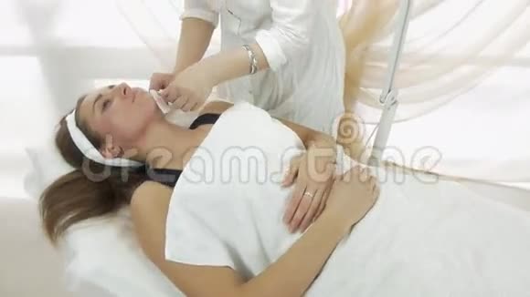 成年女性美容师在美容院做打蜡女孩下巴中型射击视频的预览图