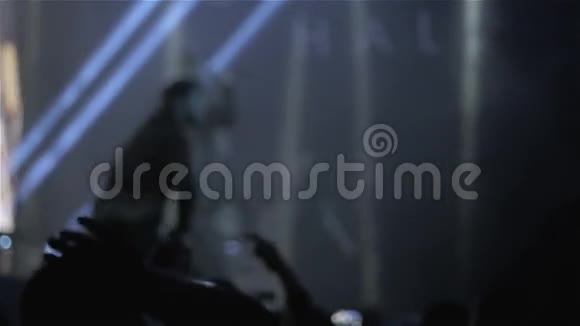 在音乐节上观众举起双手灯光从舞台上方流下来模糊的背景视频的预览图