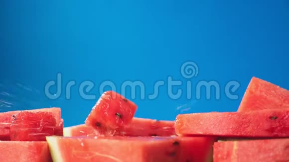 蓝色背景下多汁的红色西瓜片特写慢动作视频的预览图