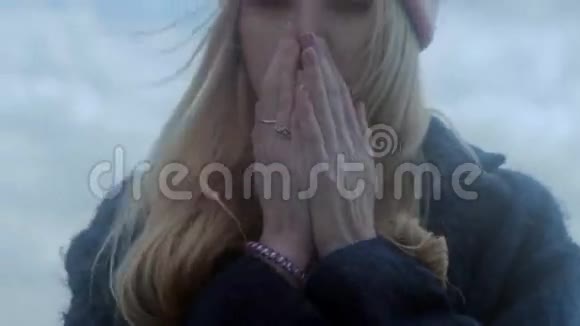 年轻的白种人女孩用呼吸温暖双手视频的预览图