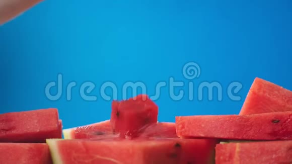 蓝色背景下多汁的红色西瓜片特写慢动作视频的预览图