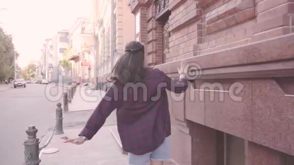 美丽的年轻开朗的女孩正在城里散步挥动双手奔跑视频的预览图
