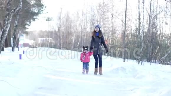 一位年轻的母亲和一个年轻的女儿在雪地森林里视频的预览图